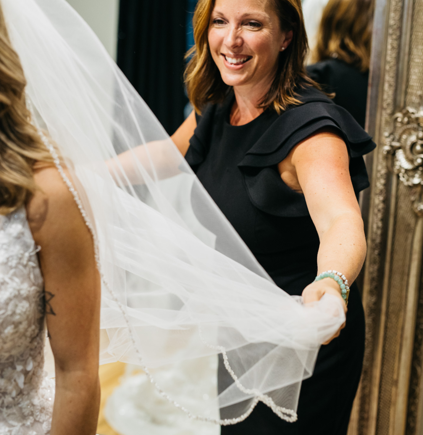 A store assistant helping a bride with a veil.