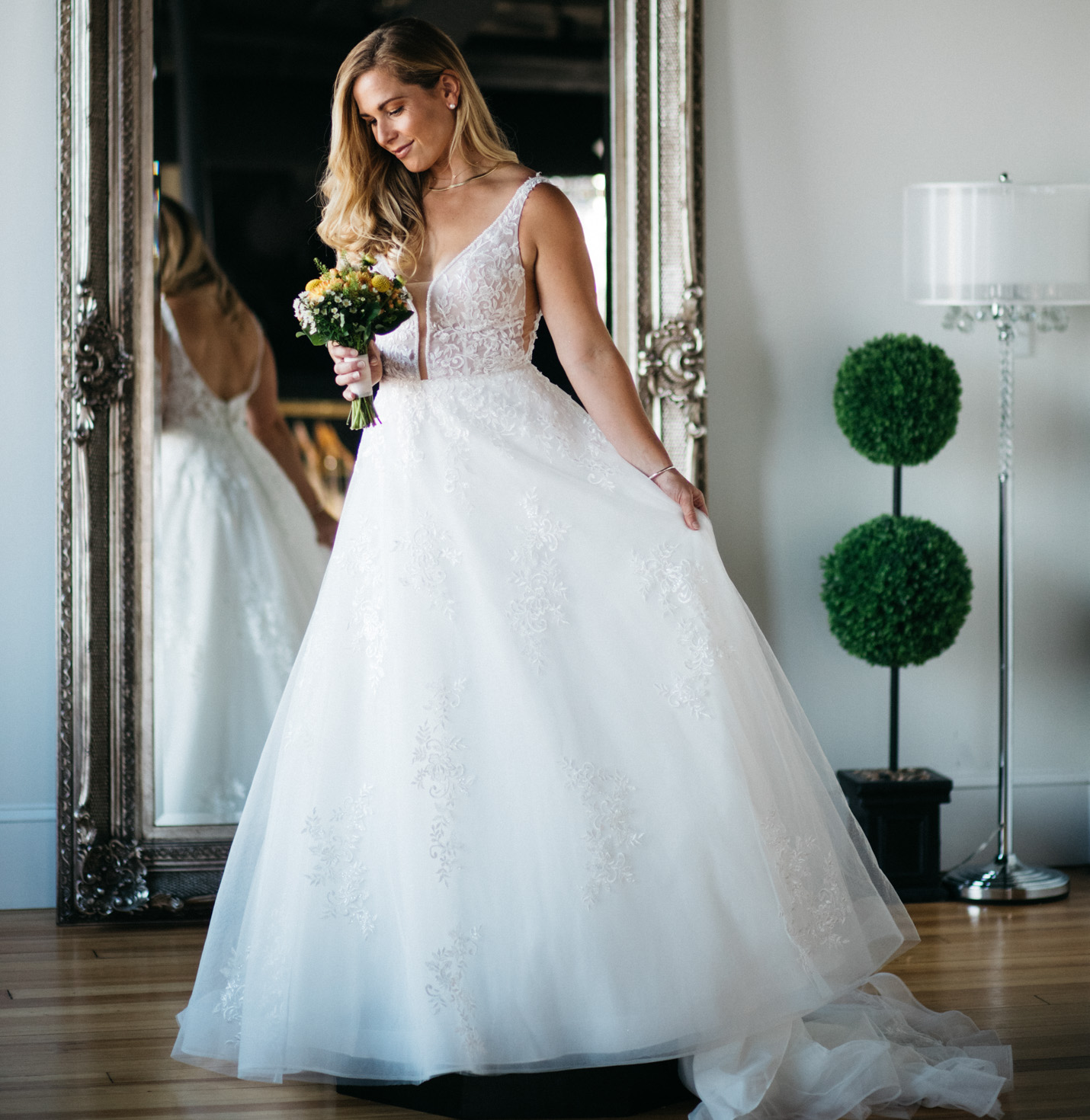 A bride trying on a dress in front of a mirror.