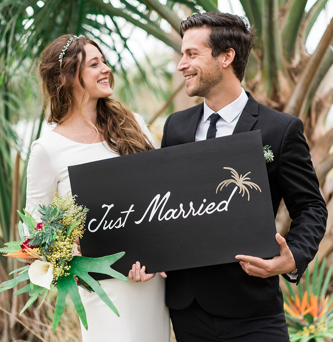A couple holding a sign that says just married.