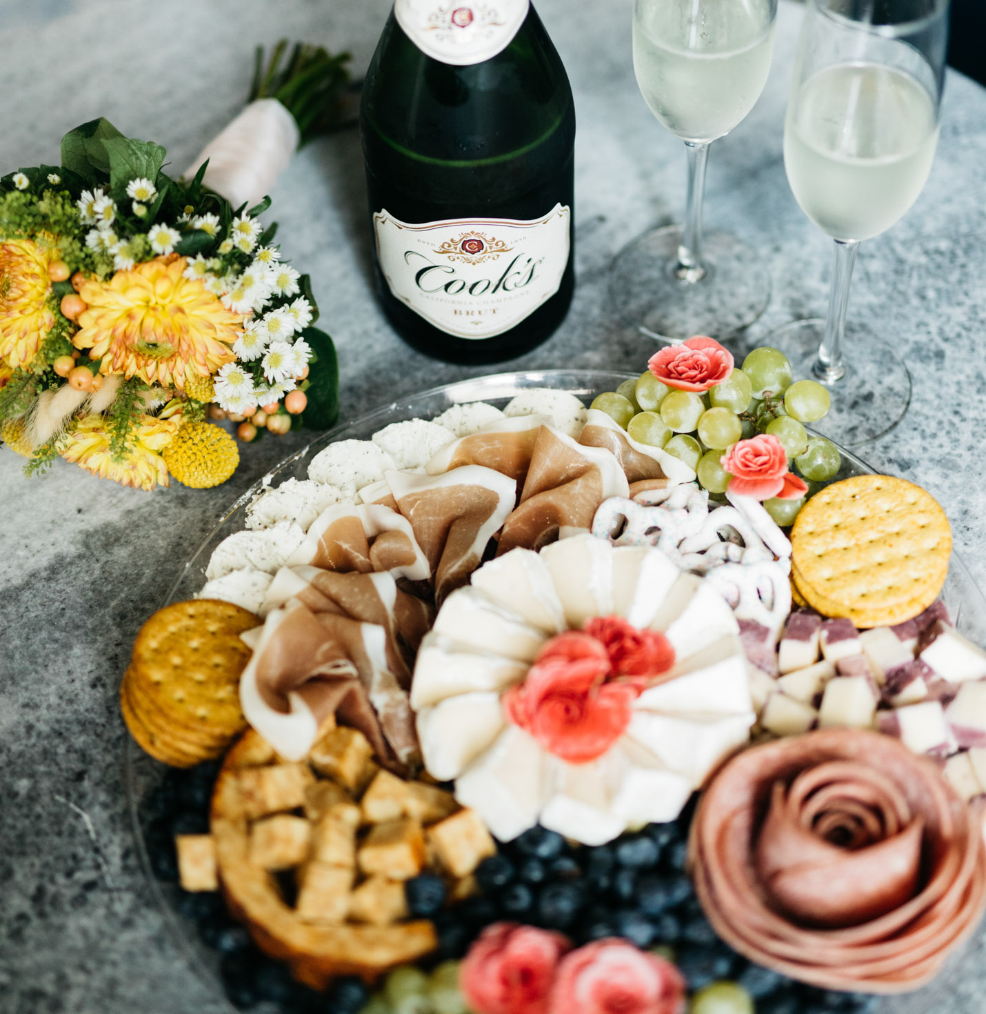 A plate of meats and cheese and champagne.