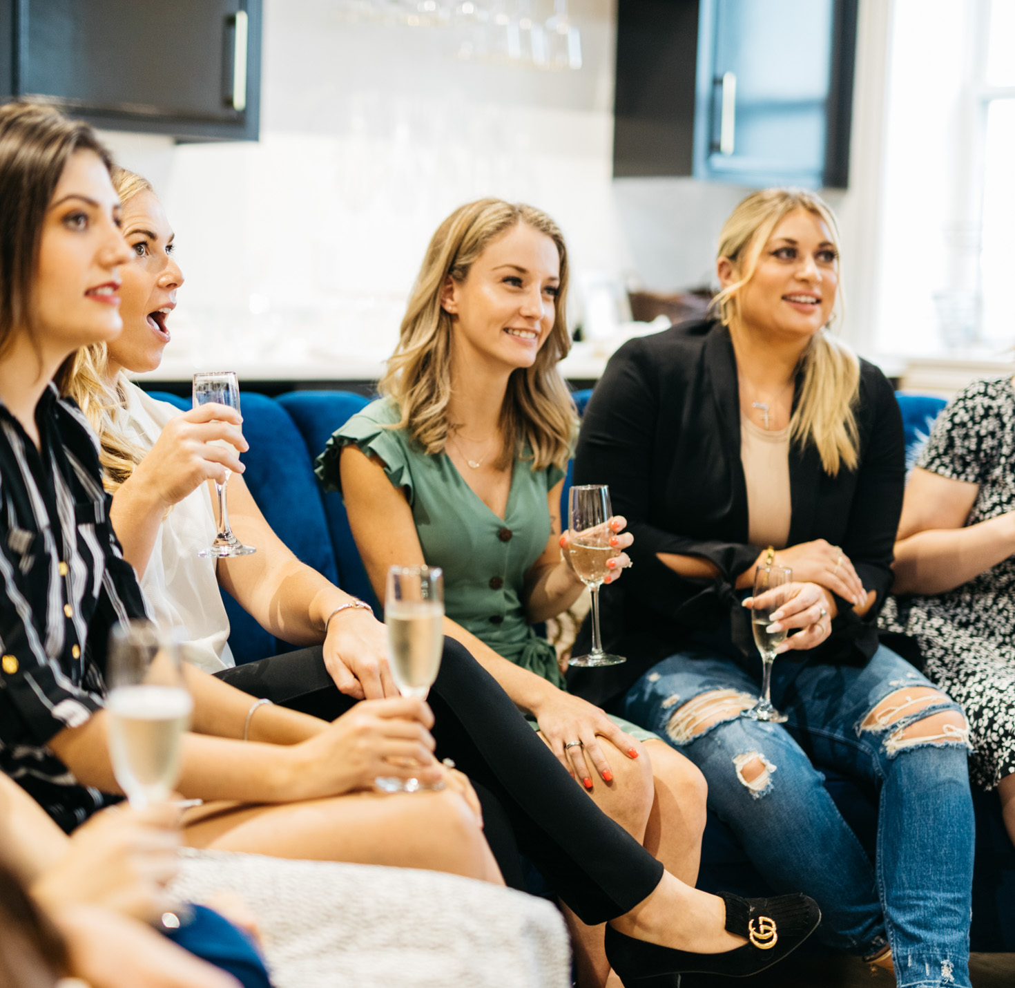 A bridal party sitting on a couch at the dress store.