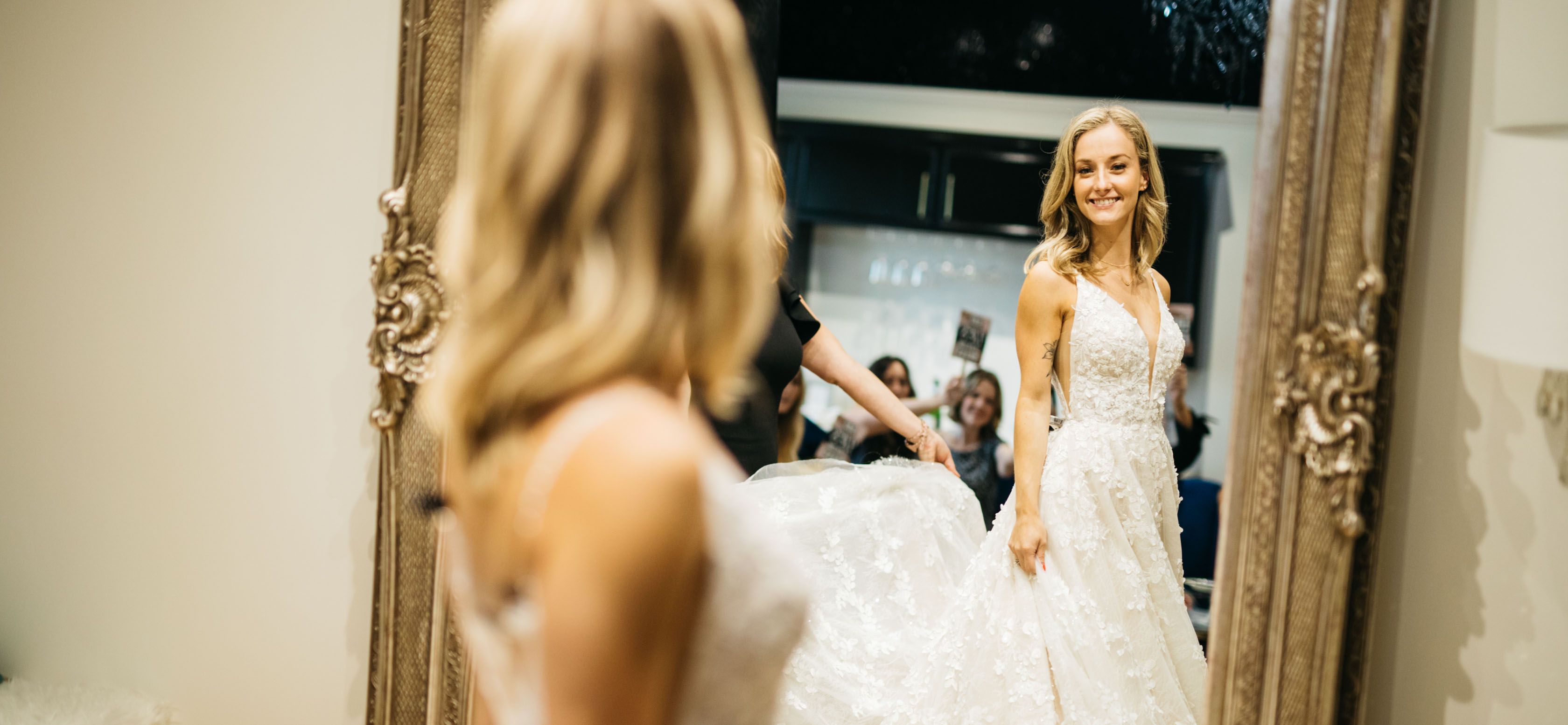 A bride looking at herself in the mirror trying on a dress.